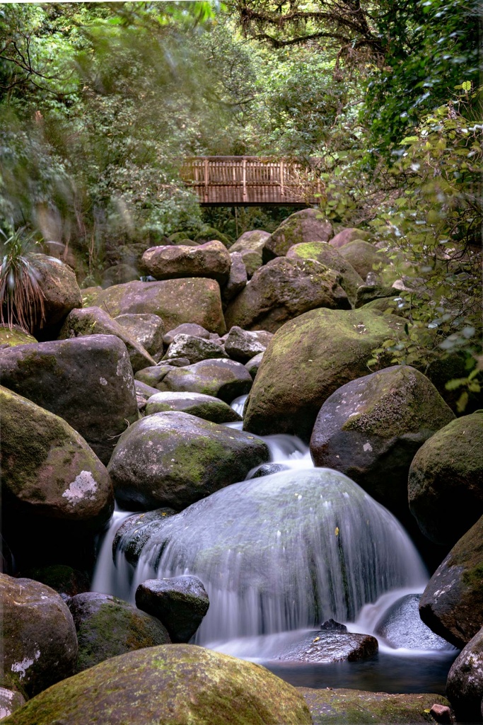 Time-lapse of water on a rock with bridge in the background